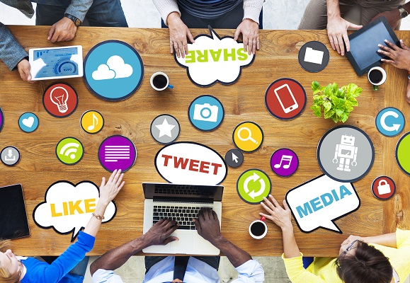 above view of employees sitting in a meeting with social media icons scattered on table